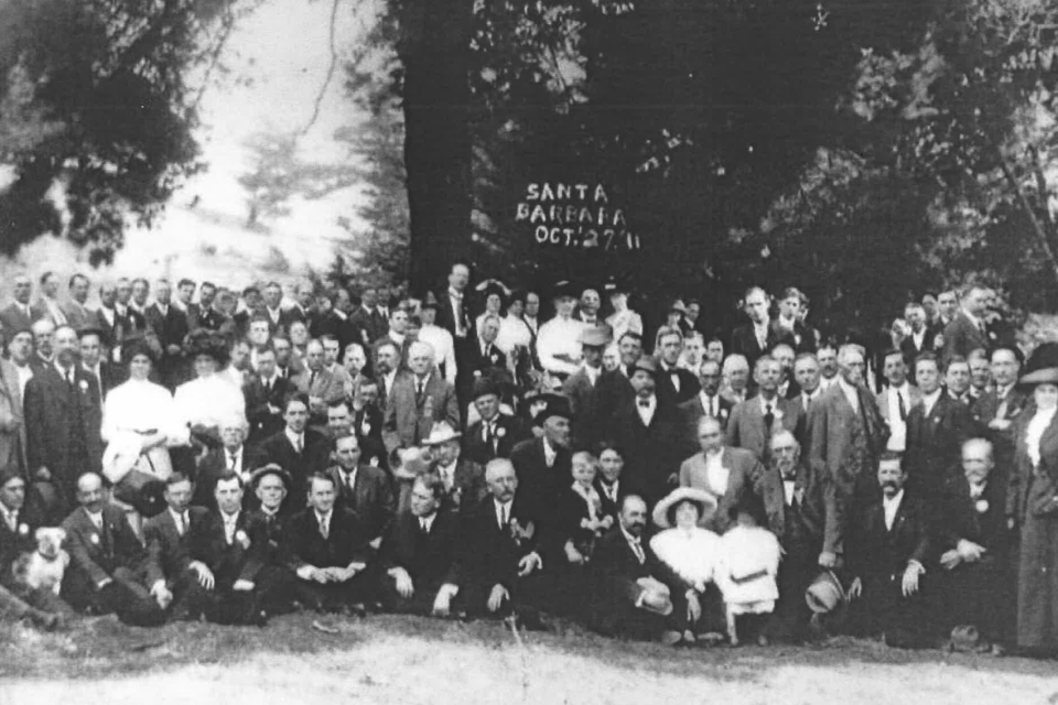 A group of mostly white men, and a few women, standing together for a photo in 1911.
